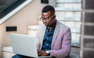 A black social worker looking contemplative while working at laptop