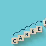 Hand putting wooden cube block on blue background with word CAREER and copy space for your text. Business career planning growth to success concept