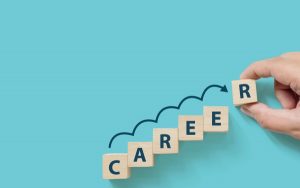 Hand putting wooden cube block on blue background with word CAREER and copy space for your text. Business career planning growth to success concept