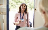 Female care worker on home visit showing her ID, close up