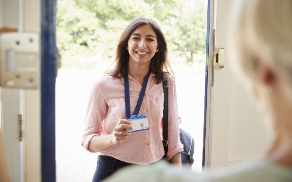 Female care worker on home visit showing her ID, close up