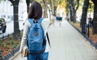 a student walking down a tree-lined walkway