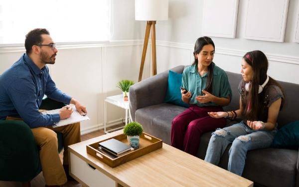 A professional man talking to a mother and child