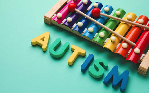 Word AUTISM and xylophone on color background