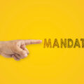 A man's pointing hand next to the inscription mandatory on yellow background