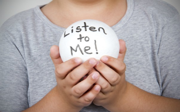 Child holding a ball that says 'listen to me'