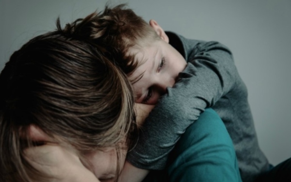 sad child hugging parent with their head turned away