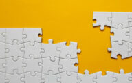 An incomplete jigsaw against a yellow background
