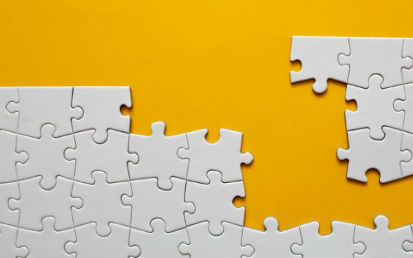 An incomplete jigsaw against a yellow background