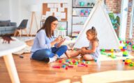 Young therapist woman speaking and treating child, counselor and behaviour correction at pedagogue payroom taking notes on clipboard
