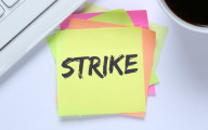 Post-it note on a table with the word 'STRIKE' written on it