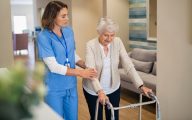 Nurse helping woman rehabilitate in care home