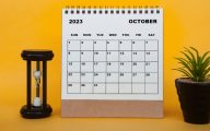 Calendar showing the month October 2023 with a sandtimer and plant