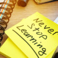 Never stop learning written on a memo stick. Lifelong learning concept.