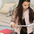 A teenage girl looks at a photo book at Christmas.