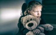 Sad small child hugging teddy