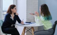 Image of social worker in school talking to teenager (credit: Valerii Honcharuk / Adobe Stock)