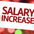 Man holding up a sign which reads 'salary increase'