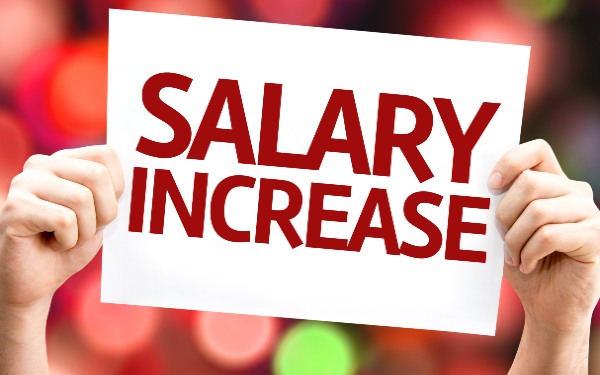 Man holding up a sign which reads 'salary increase'