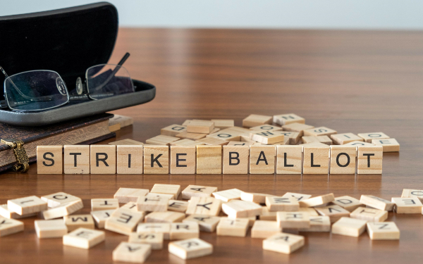 strike ballot word or concept represented by wooden letter tiles on a wooden table with glasses and a book