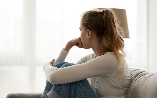 Image of teenager looking sadly towards window (credit: fizkes / Adobe Stock)