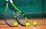 wo tennis rackets and balls leaned against the net.