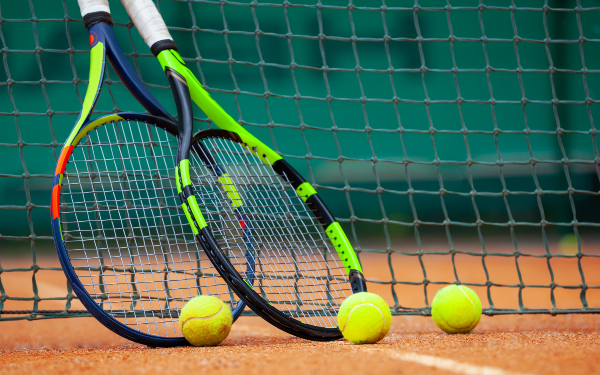 wo tennis rackets and balls leaned against the net.