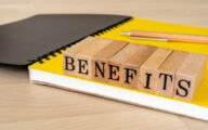 The word 'benefits' spelt out in blocks on top of the yellow page of a notepad