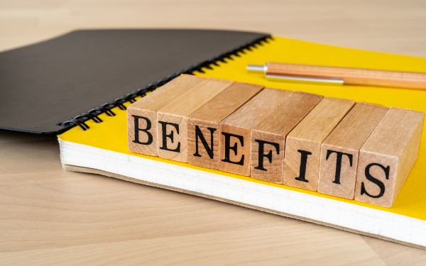The word 'benefits' spelt out in blocks on top of the yellow page of a notepad
