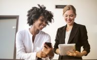 A white and a Black woman talking in the workplace