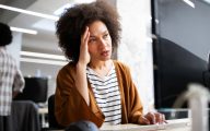 Overworked and frustrated young business woman in front of computer in office