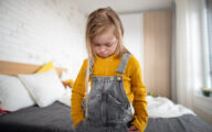 A sad little girl with Down syndrome looking down at home.