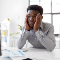 Nervous social worker holding his head in his hands while looking at a computer screen